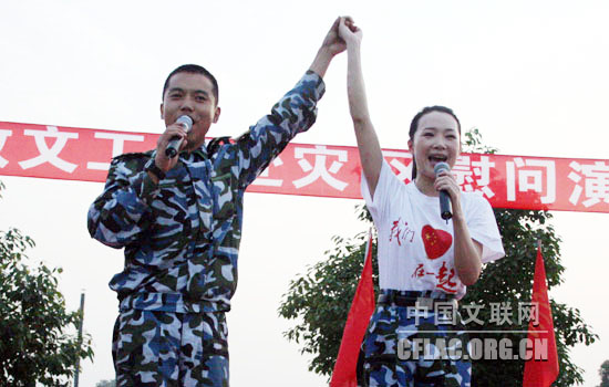 6月1日下午,海政文工团组织艺术家赴四川绵竹灾区慰问演出。图为吕薇把和她一起合唱的海军陆战队战士的手高高擎起,向全体官兵致敬。中国文联网 彭宽 摄